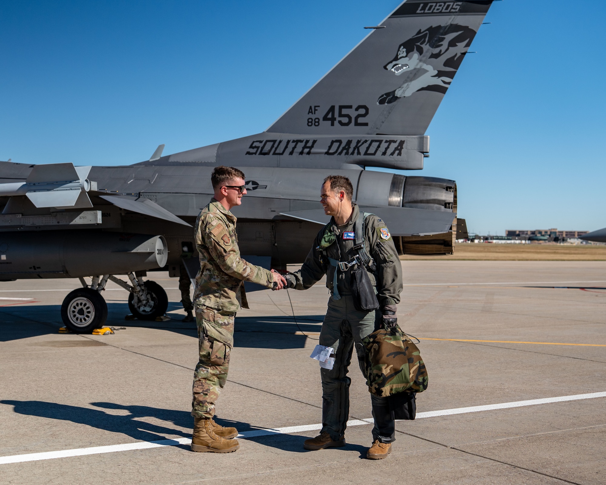 Staff Sgt. Mason Mathieu, left, dedicated crew chief with the 114th Aircraft Maintenance Squadron, shakes hands with Col. Brandon Eskam, commander of the 114th Fighter Wing, both with the South Dakota Air National Guard, beside tail 452 prior to the sortie marking the jet’s 10,000 flight hour milestone at Joe Foss Field, South Dakota, Oct. 17, 2025.