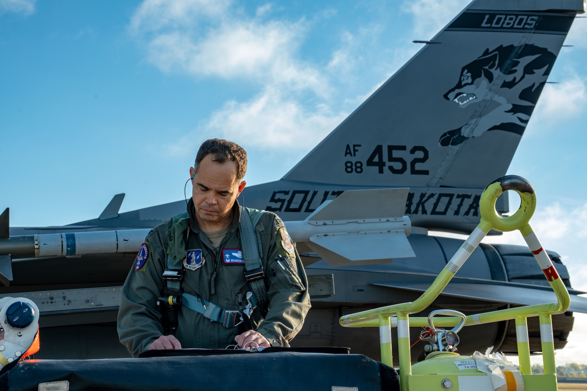 Col. Brandon Eskam, commander of the 114th Fighter Wing, South Dakota Air National Guard, reviews paperwork near tail 452 before flying the sortie surpassing the jet’s 10,000 flight hour milestone at Joe Foss Field, South Dakota, Oct. 17, 2025.