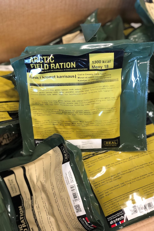 A box is filled with plastic-wrapped food rations with labels that read, "Arctic Field Ration."