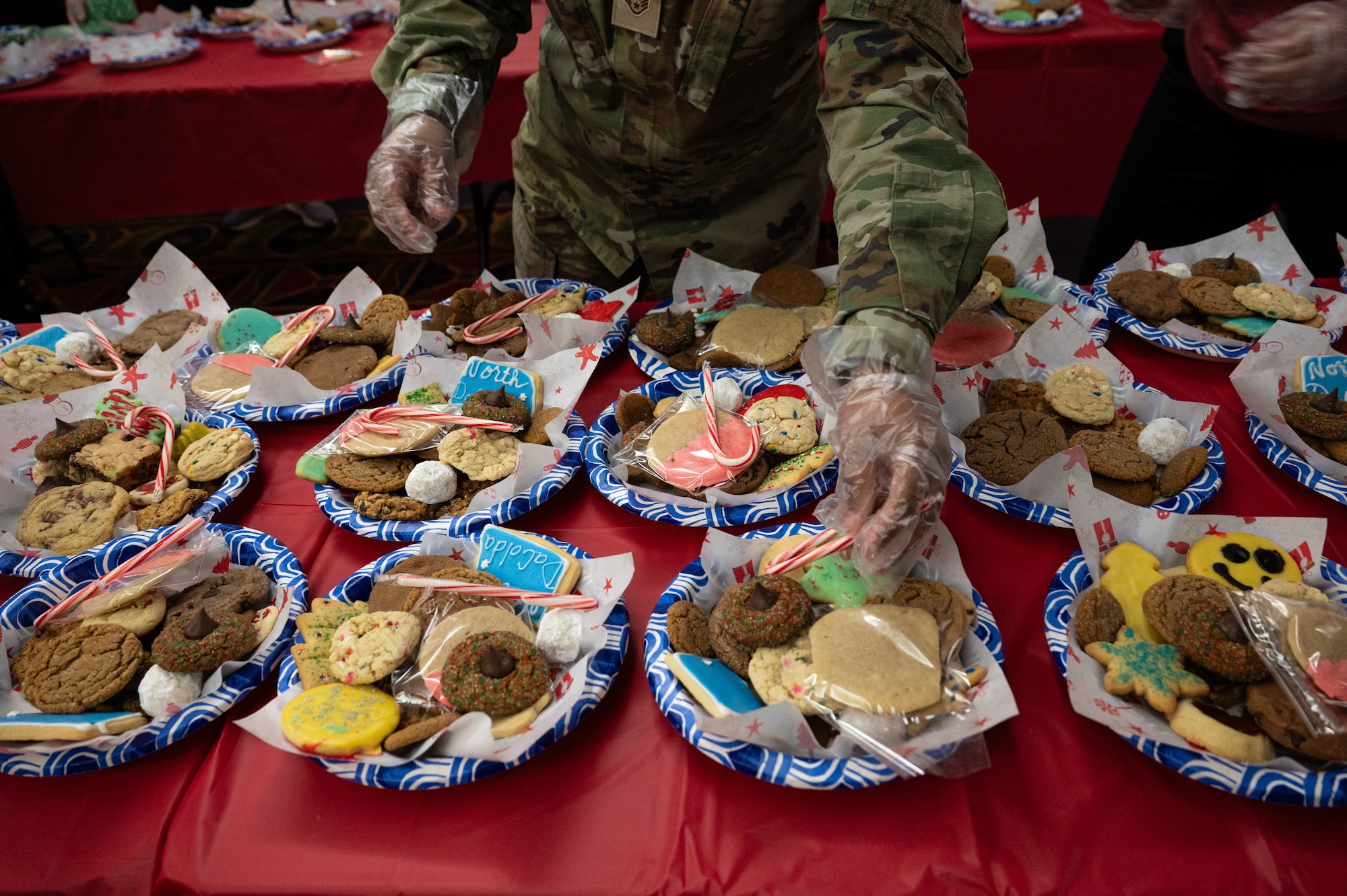 A photo of a person passing cookies out to different plates on a table.