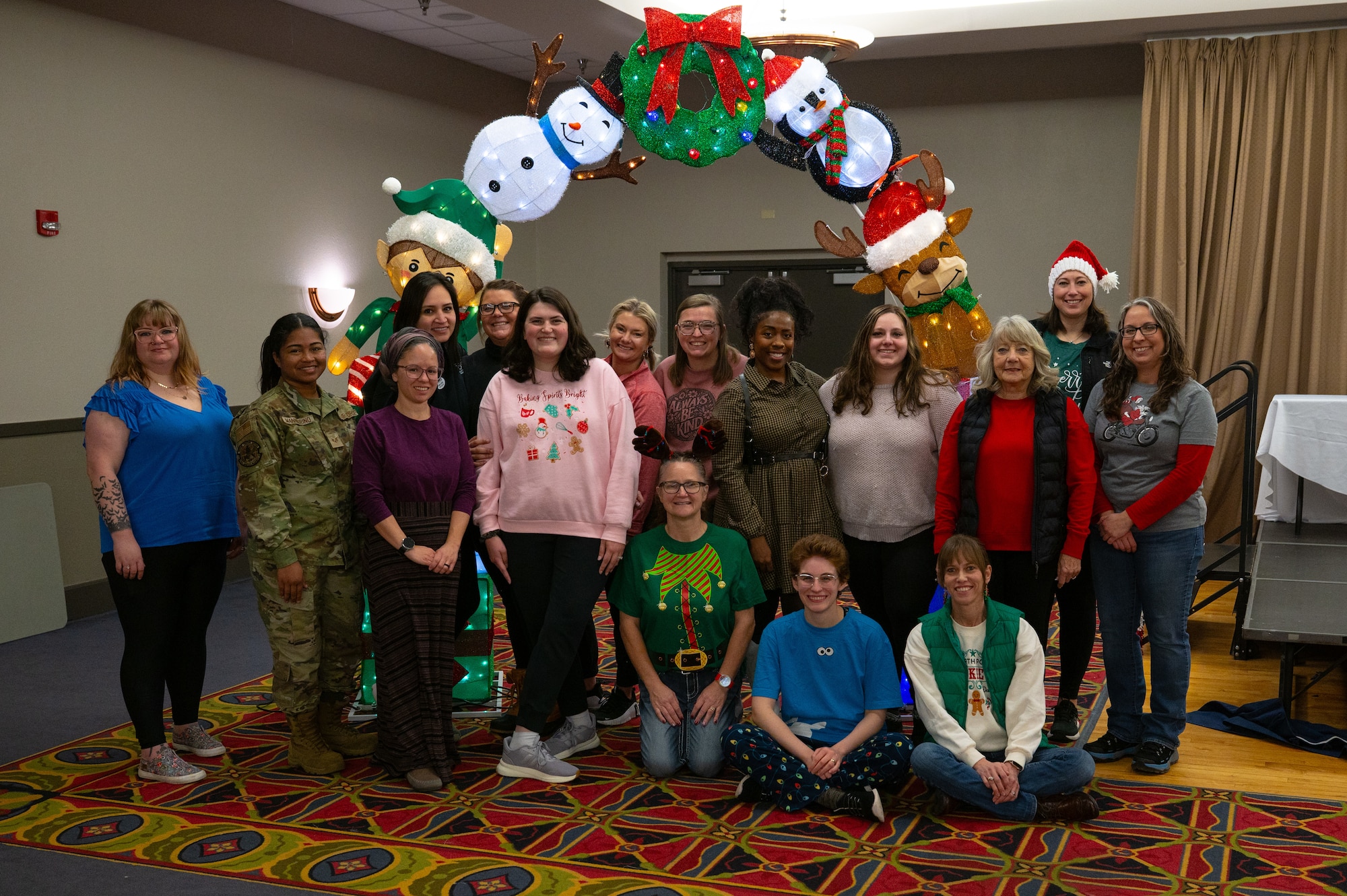 A photo of a group of people standing in front of Christmas decor.