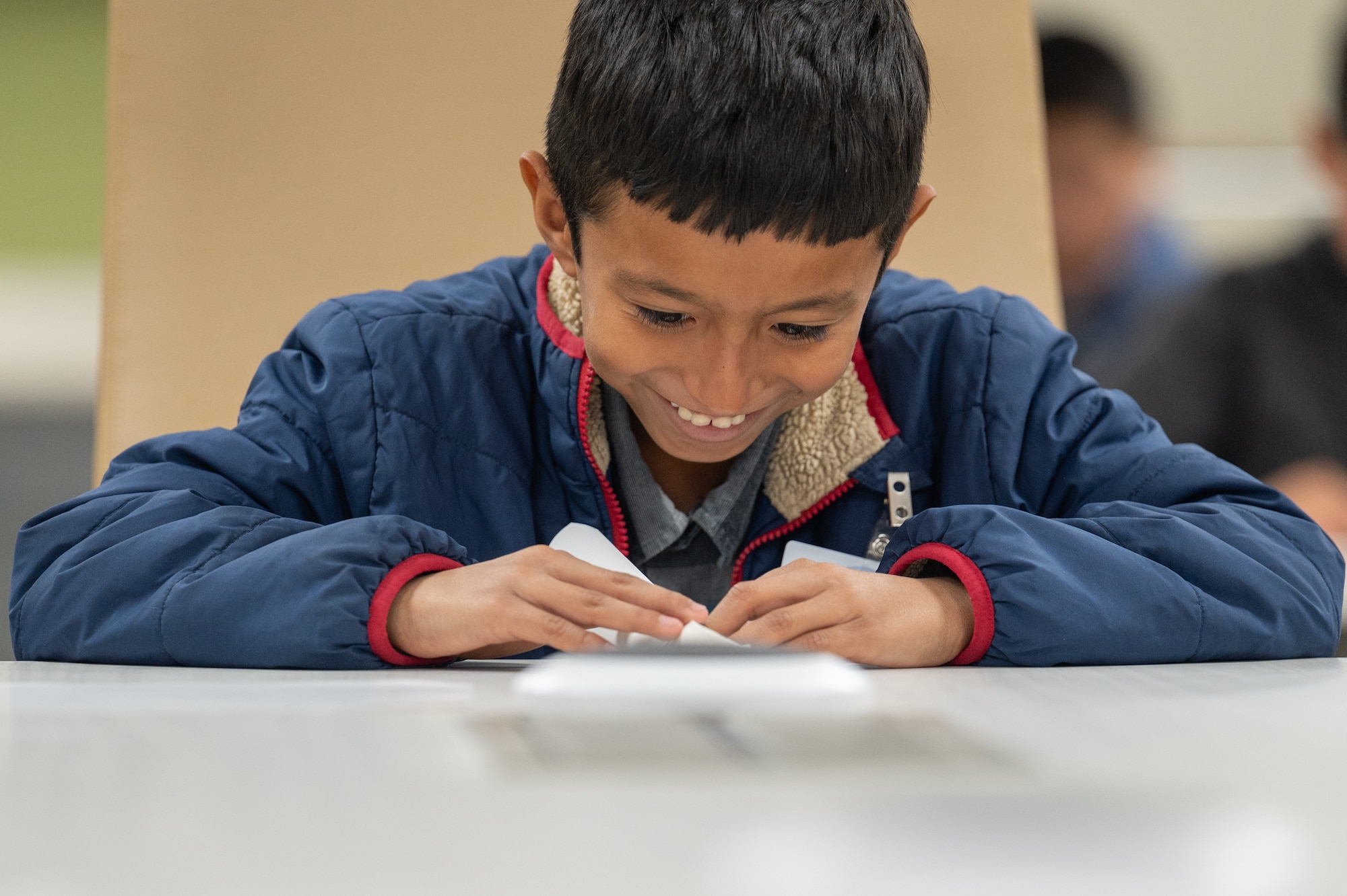 A STARBASE Edwards student from East Side Elementary in Lancaster, Calif., smiles as he folds a paper airplane