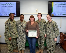Registered Nurse Angela Williams, center, is pictured with her fellow Inpatient Mental Health employees at Naval Medical Center Camp Lejeune on Nov. 24, 2025. Williams was awarded the DAISY Award, a national recognition that honors nurses for their lasting impact on their patients. Williams was nominated by a patient's family for her "deeply human approach to care." NMCCL has provided more than 80 years of dedicated, passionate care for warfighters and beneficiaries at Marine Corps Base Camp Lejeune.