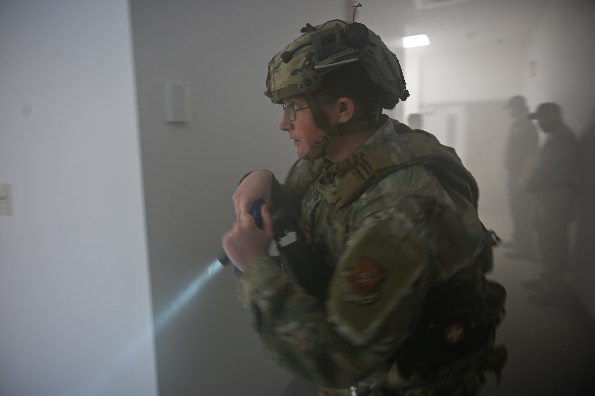 Uniformed personnel holds a flashlight.