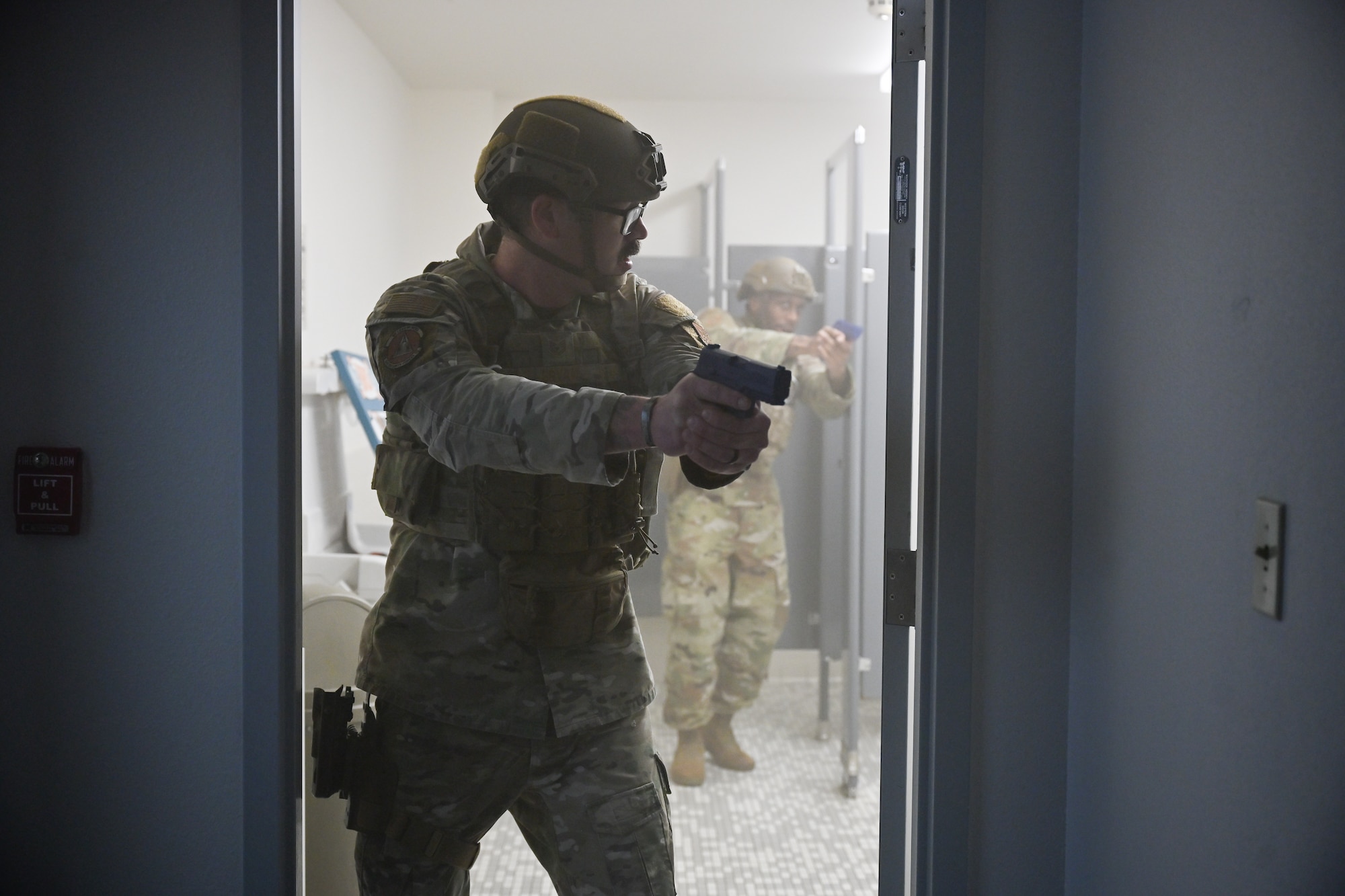 Uniformed personnel holds training weapon in bathroom.