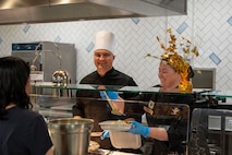 Two Airmen serve a customer a meal for Thanksgiving.