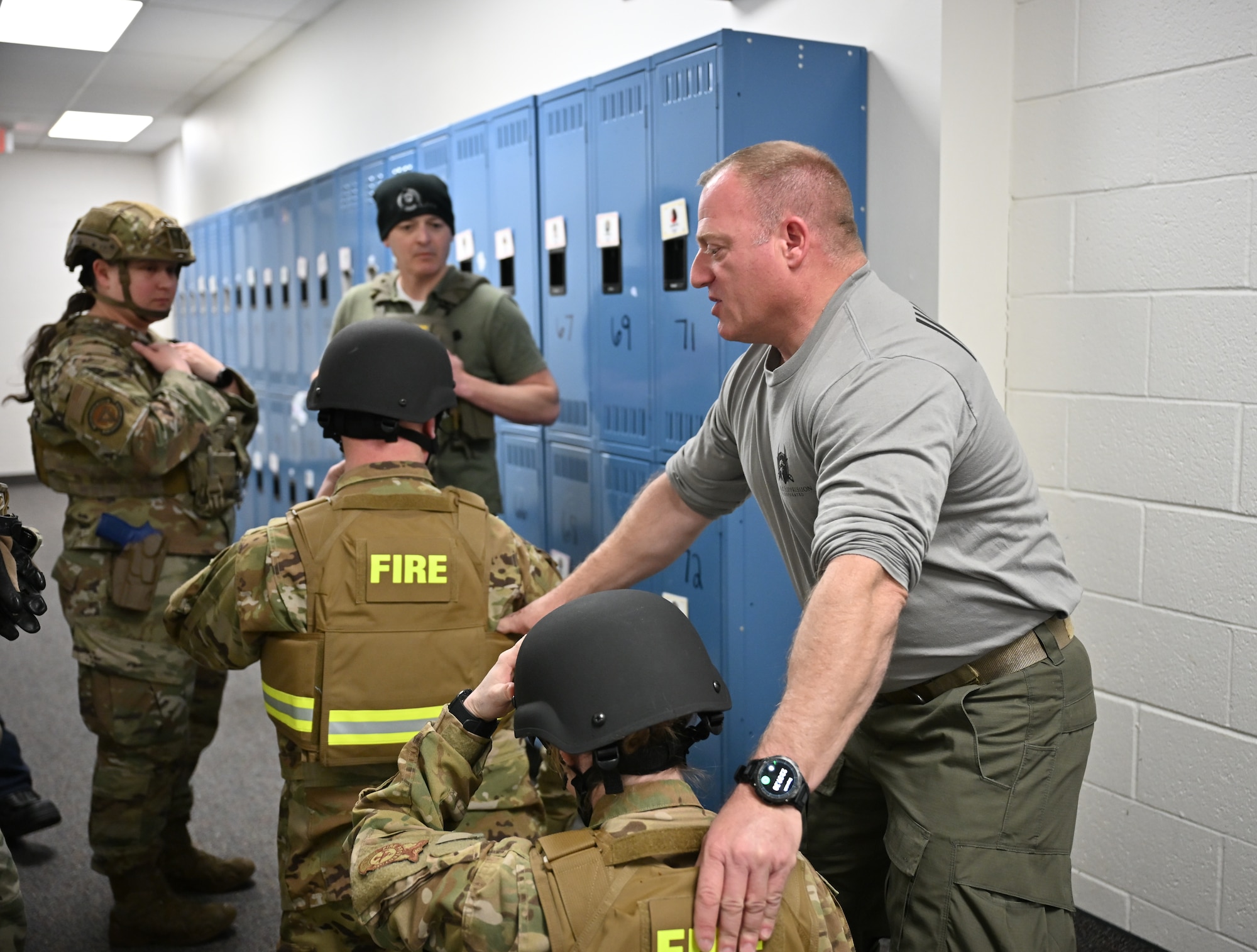 Civilian man assist uniformed personnel in training demonstration.