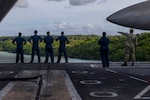 U.S. Navy Sailors look out over Guam on the flight deck of Nimitz-class aircraft carrier USS Abraham Lincoln (CVN 72) while mooring for a scheduled port visit in Guam, Dec. 11, 2025.