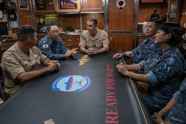 Capt. Geonyoung Ahn, commanding officer of the Republic of Korea (ROK) submarine Ahn Mu (SS 085), center-left, speaks with Cmdr. AJ Franz, commanding officer of Los Angeles-class fast-attack submarine USS Jefferson City (SSN 759), left, and Cmdr. Greg Storer, commanding officer of Los Angeles-class fast-attack submarine USS Springfield (SSN 761), center, during a visit aboard Springfield for Exercise Silent Shark 2025.