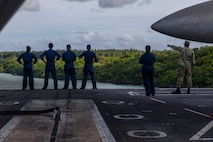 U.S. Navy Sailors look out over Guam on the flight deck of Nimitz-class aircraft carrier USS Abraham Lincoln (CVN 72) while mooring for a scheduled port visit in Guam, Dec. 11, 2025.