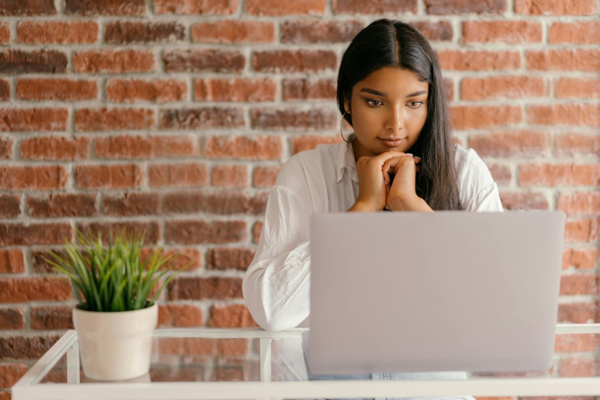 Woman looks at a laptop while she sits at a table.