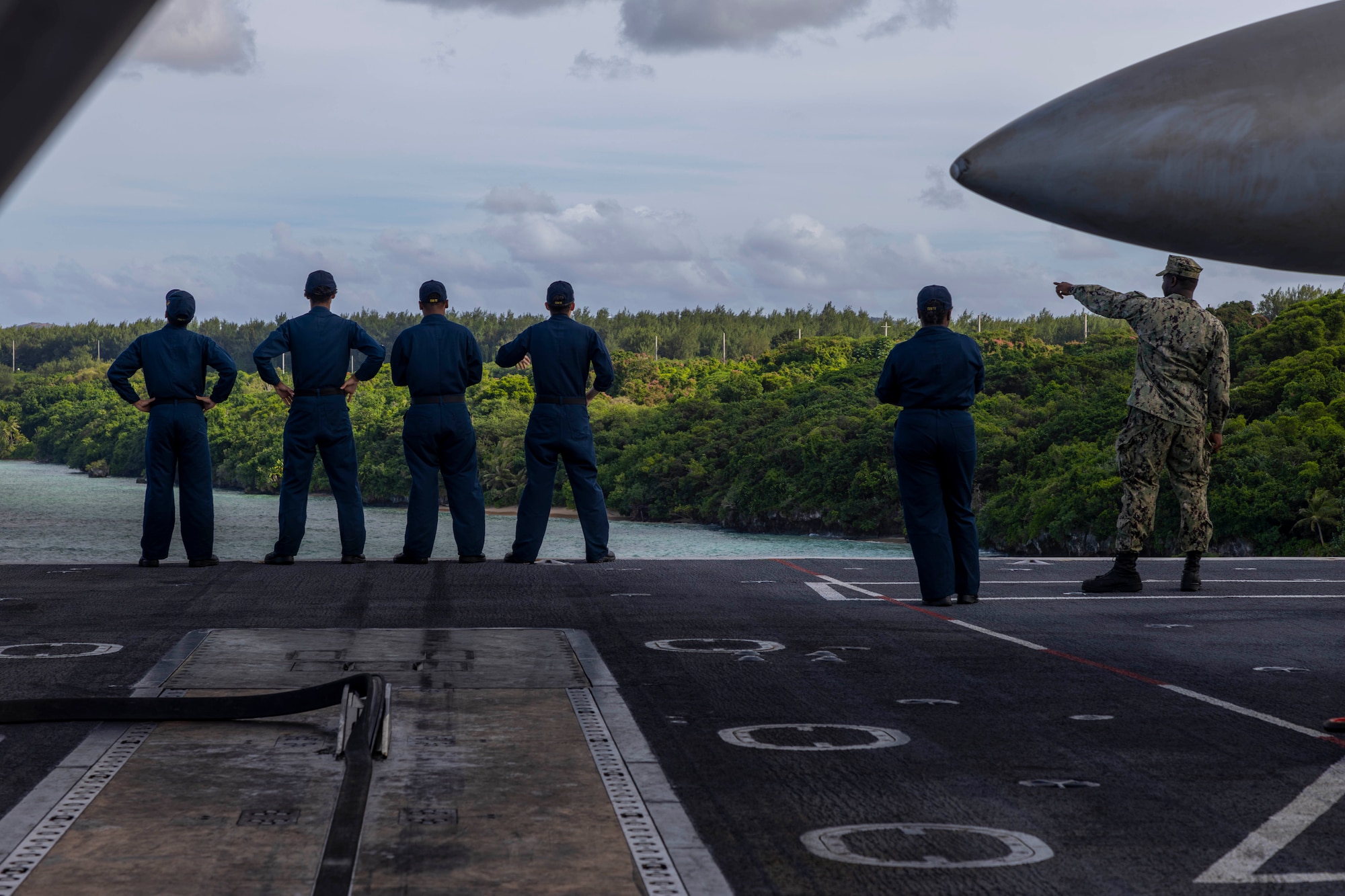 U.S. Navy Sailors look out over Guam on the flight deck of Nimitz-class aircraft carrier USS Abraham Lincoln (CVN 72) while mooring for a scheduled port visit in Guam, Dec. 11, 2025. The Abraham Lincoln Carrier Strike Group is underway conducting routine operations in the U.S. 7th Fleet area of operations. Units assigned to 7th Fleet conduct regular Indo-Pacific patrols to deter aggression, strengthen alliances and partnerships, and advance peace through strength. (U.S. Navy photo by Mass Communication Specialist Seaman Daniel Kimmelman)