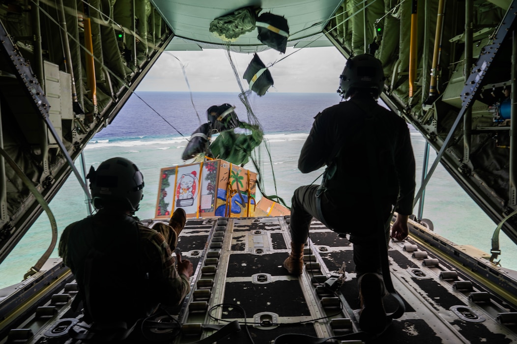 From left, U.S. Air Force Senior Airmen Mark Weinstein and Cody Raymond, 374th Air Expeditionary Wing loadmasters, drop humanitarian bundles.