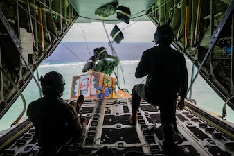 From left, U.S. Air Force Senior Airmen Mark Weinstein and Cody Raymond, 374th Air Expeditionary Wing loadmasters, drop humanitarian bundles.