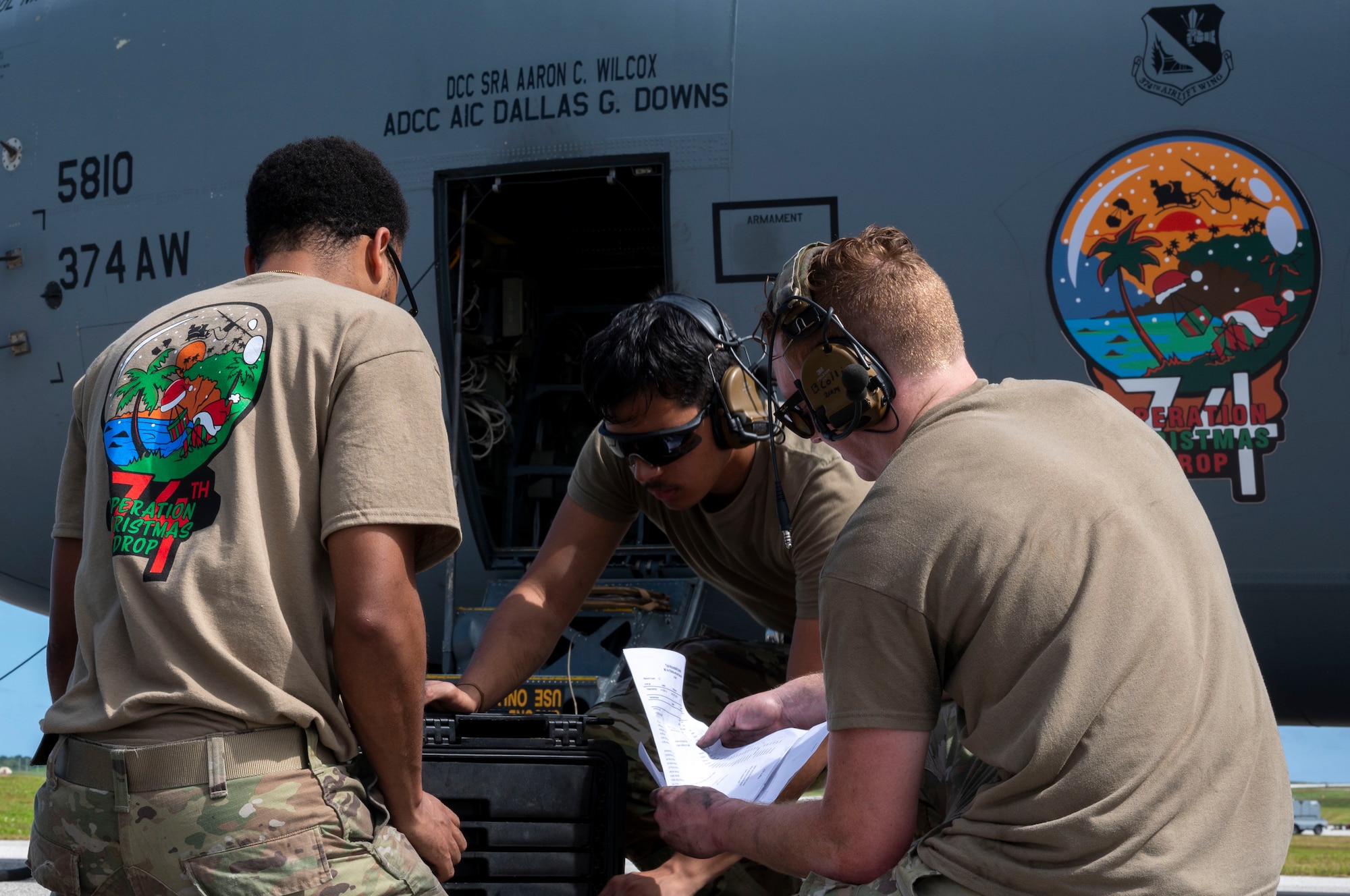 Three military members conduct maintenance work on a C-130J aircraft.