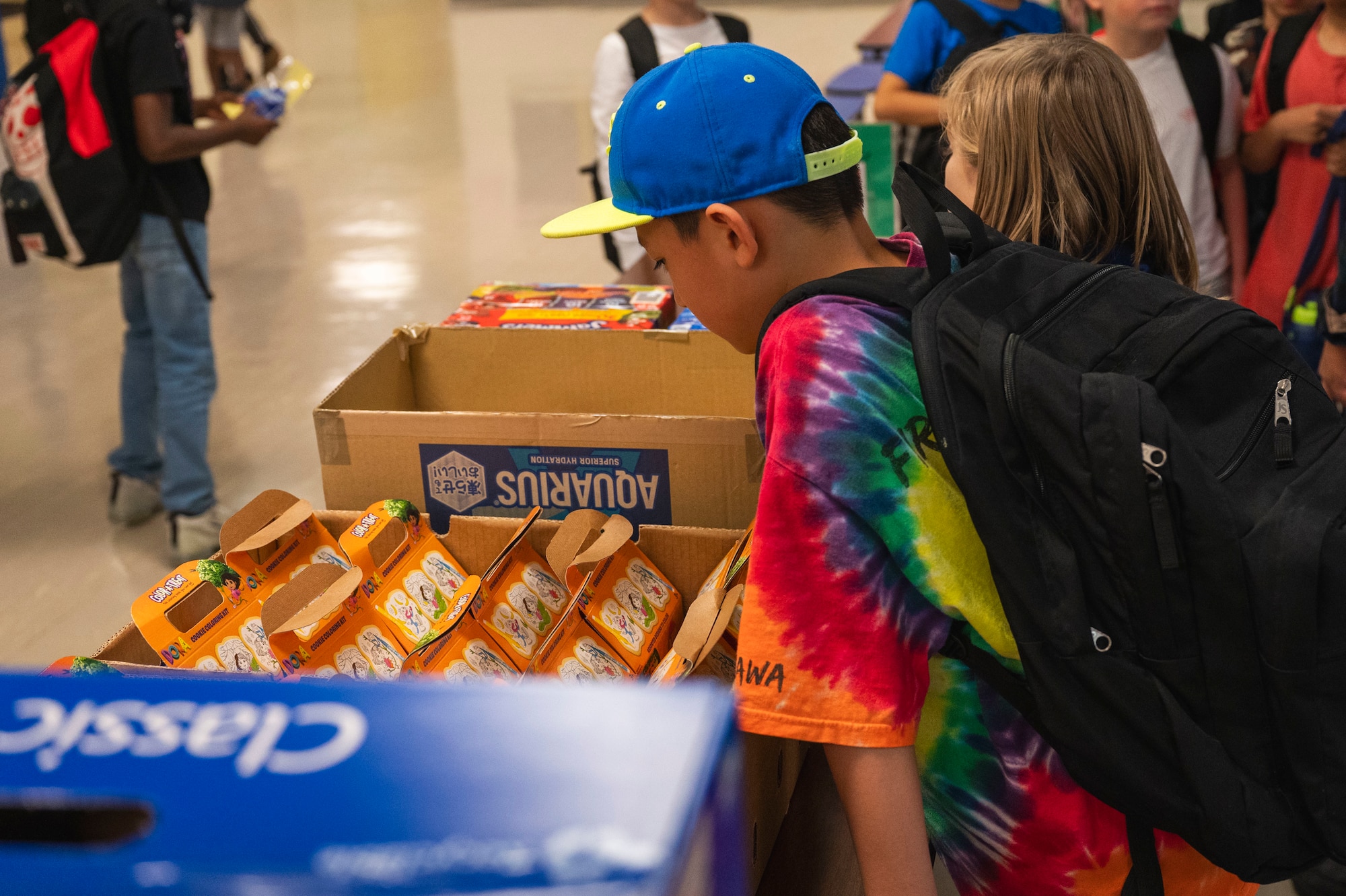 A child leans over a box of snacks.