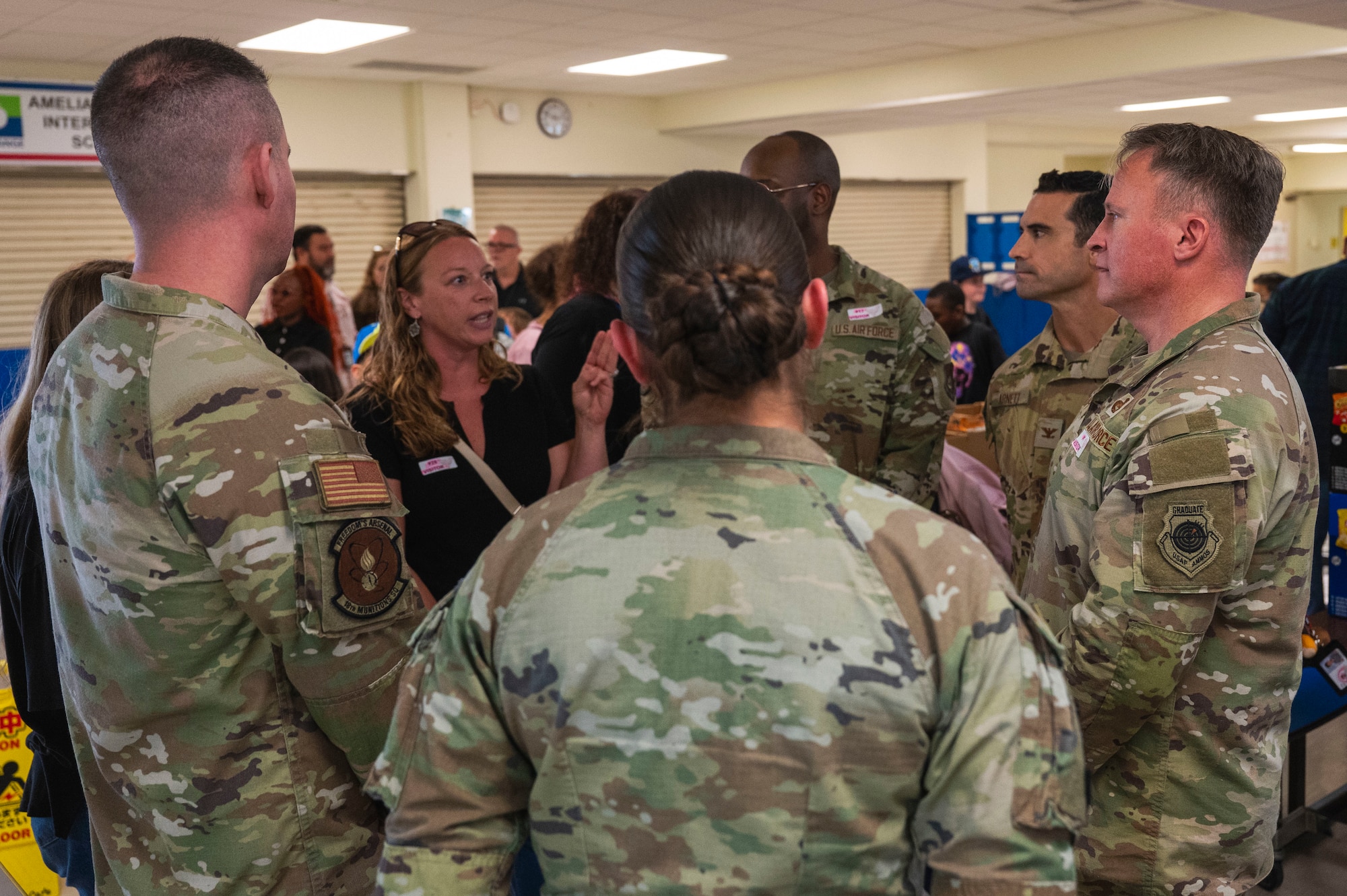 A group of service members listen to a school teacher.
