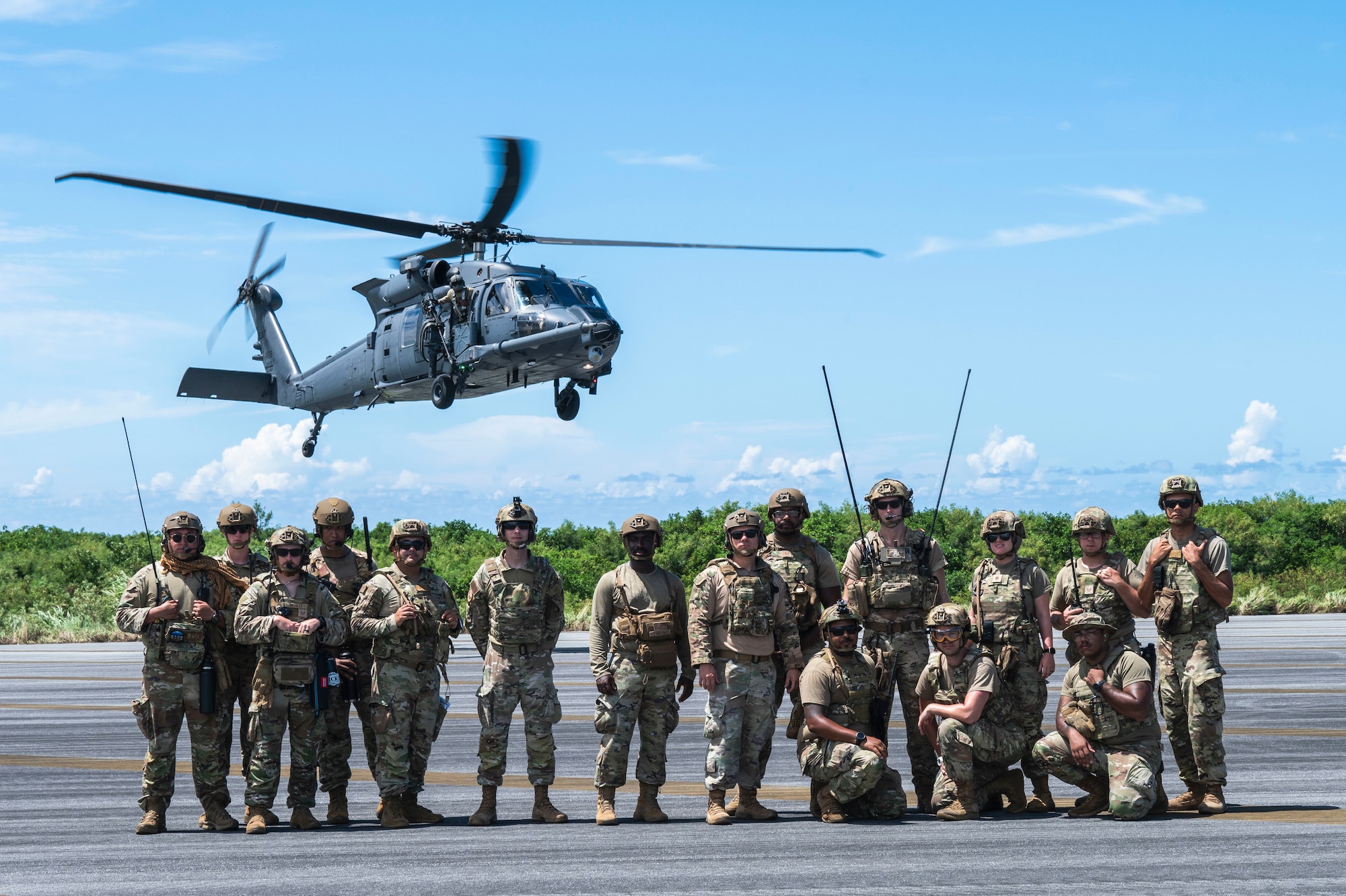 Airmen and a helicopter pose for a photo