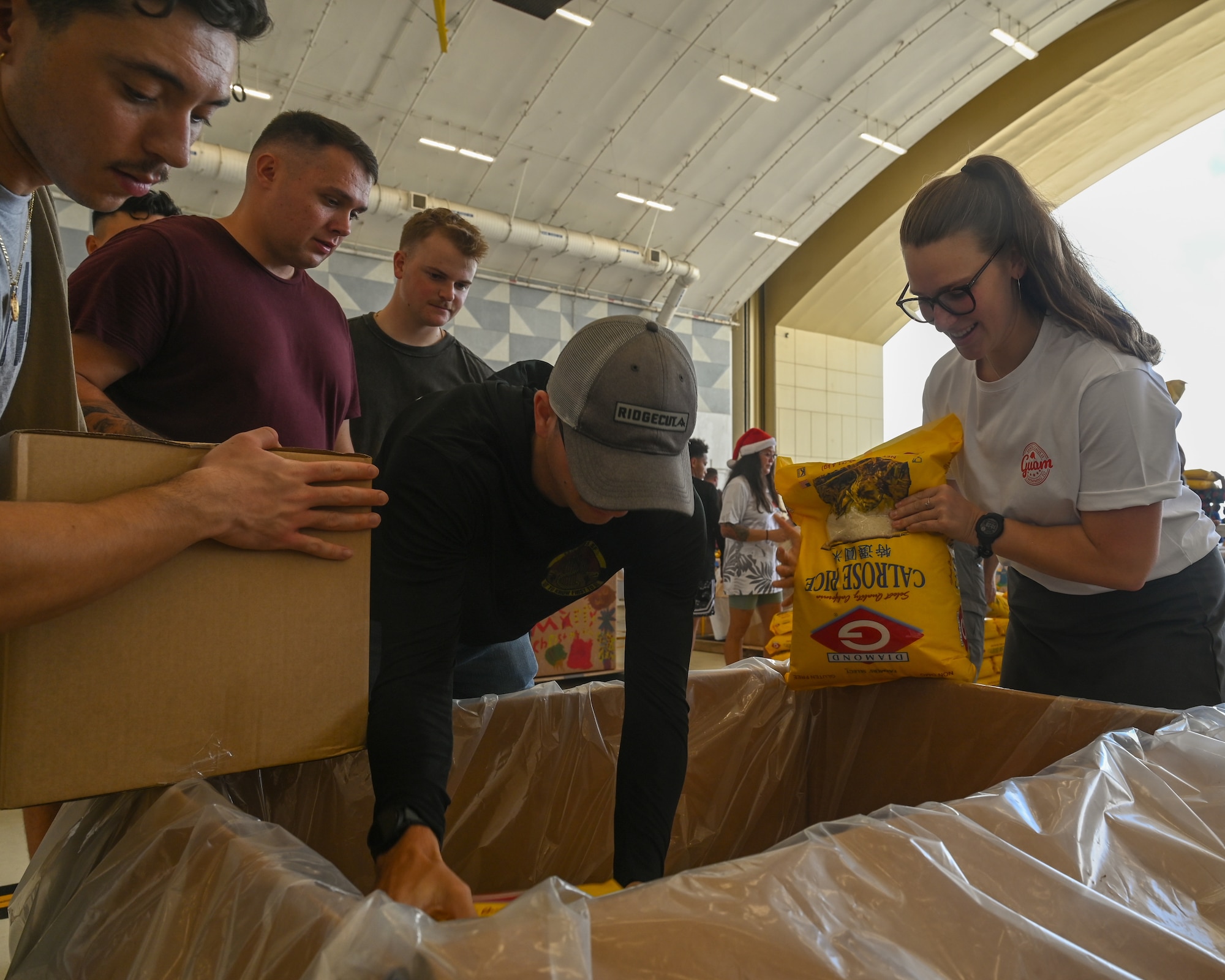 Senior Airman Colby Fox, a response force leader for 11th Combat Air Base Squadron, places books in their unit bundle during Operation Christmas Drop 2025 at Andersen Air Force Base, Guam, Dec. 6, 2025.