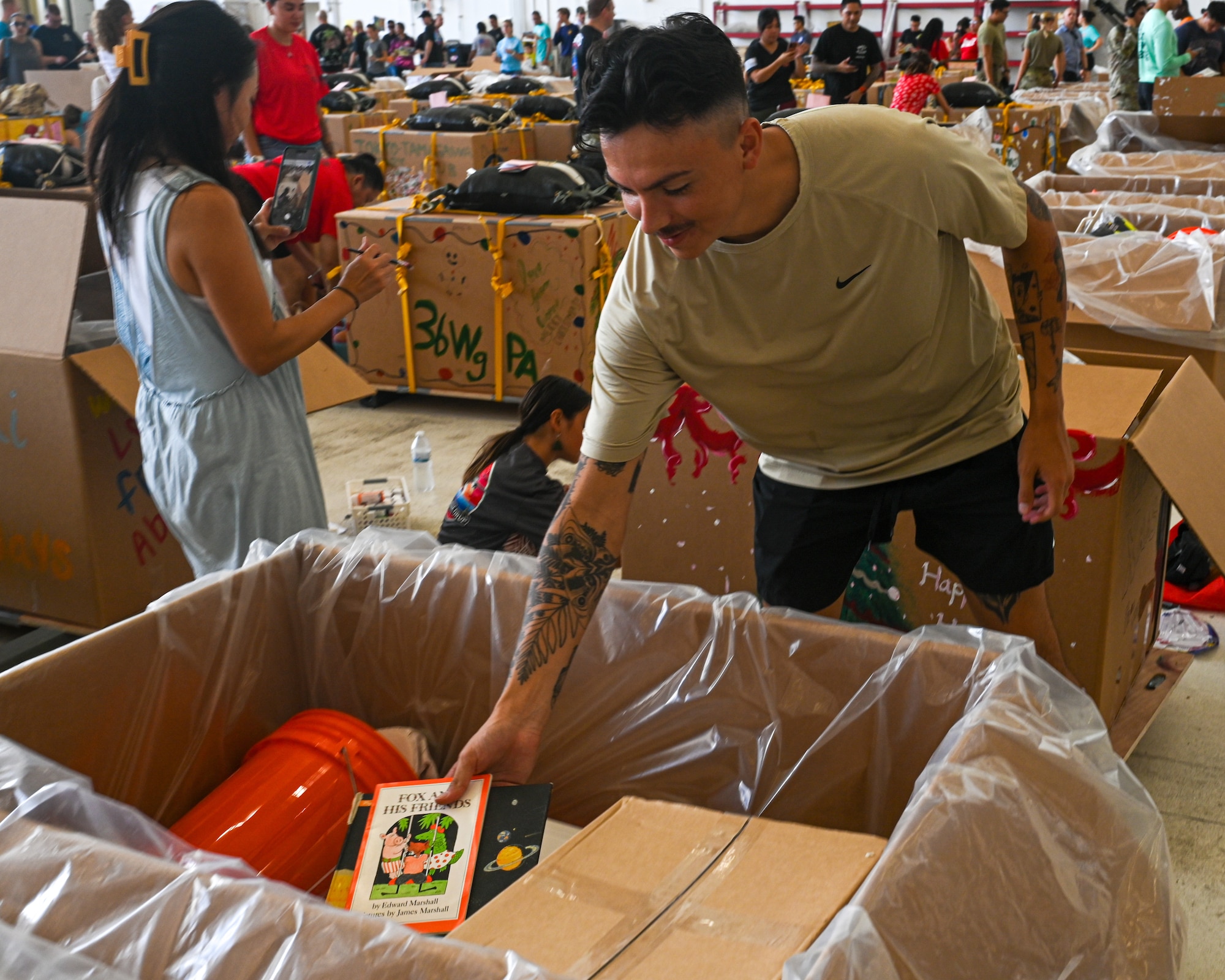 Senior Airman Colby Fox, a response force leader for 11th Combat Air Base Squadron, places books in their unit bundle during Operation Christmas Drop 2025 at Andersen Air Force Base, Guam, Dec. 6, 2025.