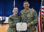 YOKOSUKA, Japan (Nov. 19, 2025) — Hospitalman Apprentice Skylar L. Foote, left, assigned to U.S. Naval Hospital Yokosuka, receives the Navy and Marine Corps Achievement Medal from Capt. Donavon YapShing, executive officer of U.S. Navy Medicine Readiness and Training Command Yokosuka and deputy director of U.S. Naval Hospital Yokosuka, during an awards ceremony. Foote was recognized for her life-saving response aboard a commercial flight in July, where she assessed, monitored, and coordinated care for a passenger experiencing medical distress until the aircraft landed safely. (U.S. Navy photo by Daniel Taylor/USNMRTC Yokosuka Public Affairs)