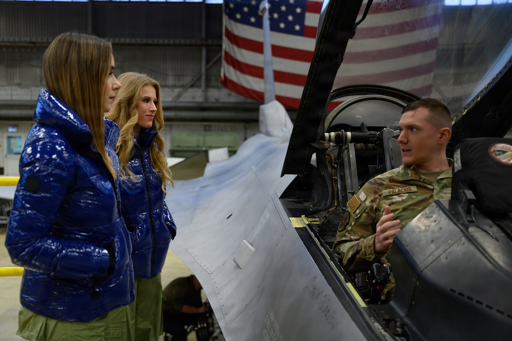 A U.S. military member sits in a plane while talking to two people.