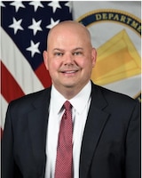 man wearing a suit in front of two flags