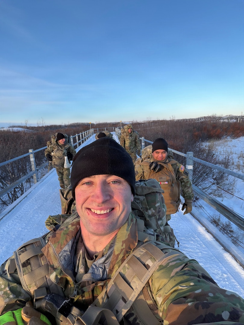 Alaska Army National Guard Spc. Brad Adams, assigned to the 297th Infantry Battalion’s Headquarters and Headquarters Company, and his team ruck march into town after landing in Tuntutuliak, Nov. 13, 2025, to support ongoing recovery operations following Typhoon Halong,
