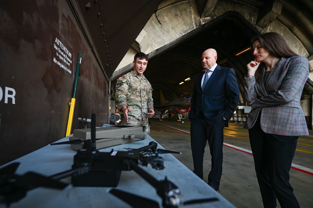 U.S. Air Force Senior Airman Carson Ruocco, 52nd Security Forces Squadron patrolman, left, briefs Mr. Brian Heath, Consul General at the U.S. Consulate General in Frankfurt, Germany, and Ms. Liana Mitlyng Day, deputy political economic section chief, on counter-drone equipment during a tour at Spangdahlem Air Base, Germany, Oct. 27, 2025.
