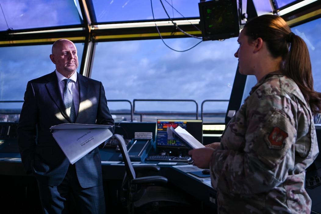 Mr. Brian Heath, consul general at the U.S. Consulate General in Frankfurt, Germany, left, receives a wing mission brief from U.S. Air Force Tech Sgt. Celeste Kennedy, 52nd Fighter Wing commander's action group superintendent, during an installation tour at Spangdahlem Air Base, Germany, Oct. 27, 2025.
