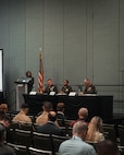 An audience observes three Marine Corps Generals participating in a panel discussion