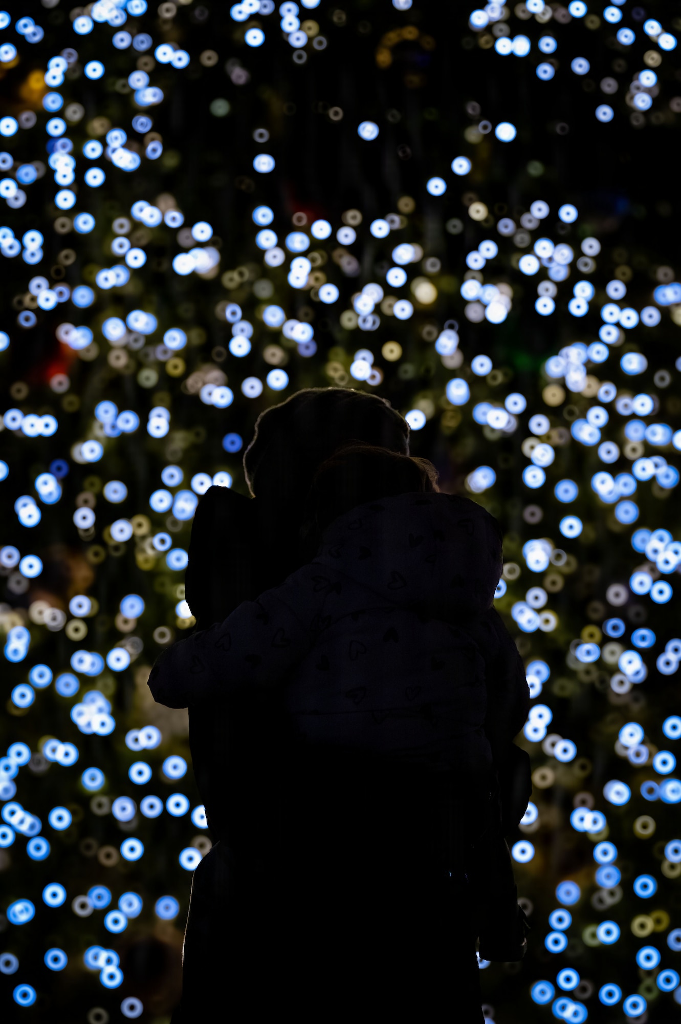 A woman holds her child during the holiday tree lighting ceremony at RAF Mildenhall, England, Dec. 5, 2025.