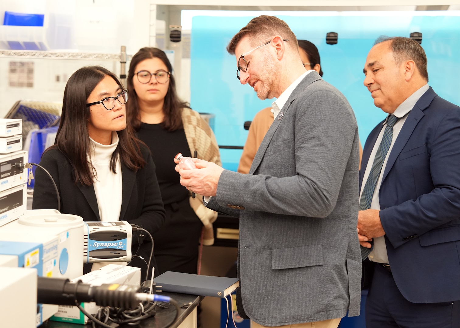 JOINT BASE SAN ANTONIO-FORT SAM HOUSTON (Dec. 8, 2025) Dr. Jeremy Pamplin, (center) program manager, Biological Technologies Office, Defense Advanced Research Projects Agency (DARPA), views a novel synthetic blood product that is being developed under DARPA’s Fieldable Solutions for Hemorrhage with bio-Artificial Resuscitation Products (FSHARP) program at the Battlefield Health & Trauma Research Institute. Naval Medical Research Unit (NAMRU) San Antonio serves as the Independent Validation & Verification partner for the FSHARP program to perform laboratory testing for safety and efficacy. The FSHARP program works to develop a deployable, shelf-stable, universal whole blood substitute as a hemorrhage countermeasure to sustain injured warfighters in austere, pre-hospital settings. NAMRU San Antonio, part of Navy Medicine Research & Development, works alongside research partners in the civilian sphere, academia, industry, and other government agencies to drive support of the Department of War’s objectives for a lethal fighting force and ensures U.S. service members have access to the latest scientific advances. NAMRU San Antonio conducts gap-driven combat casualty care, craniofacial, and directed energy research in support of Navy, Marine Corps and joint U.S. warfighter health readiness and lethality while engaged in routine and expeditionary operations. (U.S. Navy photo by Burrell Parmer/Released)