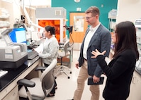 JOINT BASE SAN ANTONIO-FORT SAM HOUSTON (Dec. 8, 2025) Dr. Jeremy Pamplin, (center) program manager, Biological Technologies Office, Defense Advanced Research Projects Agency (DARPA), is briefed by research immunologist Dr. Dao Ho (right) and research scientist Phylisia Dimas, assigned to Naval Medical Research Unit (NAMRU) San Antonio on the specific methods by which NAMRU-SA assesses the viability and proliferation of living cells for DARPA’s Fieldable Solutions for Hemorrhage with bio-Artificial Resuscitation Products (FSHARP) program at the Battlefield Health & Trauma Research Institute. The FSHARP program works to develop a deployable, shelf-stable, universal whole blood substitute as a hemorrhage countermeasure to sustain injured warfighters in austere, pre-hospital settings. NAMRU San Antonio, part of Navy Medicine Research & Development, works alongside research partners in the civilian sphere, academia, industry, and other government agencies to drive support of the Department of War’s objectives for a lethal fighting force and ensures U.S. service members have access to the latest scientific advances. NAMRU San Antonio conducts gap-driven combat casualty care, craniofacial, and directed energy research in support of Navy, Marine Corps and joint U.S. warfighter health readiness and lethality while engaged in routine and expeditionary operations. (U.S. Navy photo by Burrell Parmer/Released)