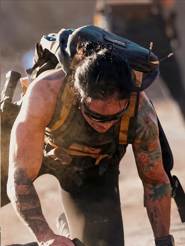 woman wearing workout gear crawls while dragging a heavy bag.