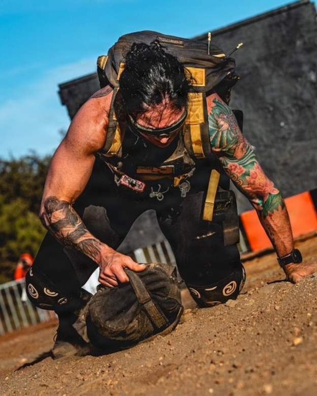 woman wearing workout gear crawls while dragging a heavy bag.