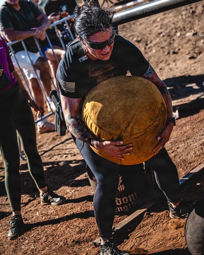 woman wearing workout gear carries a medicine ball.
