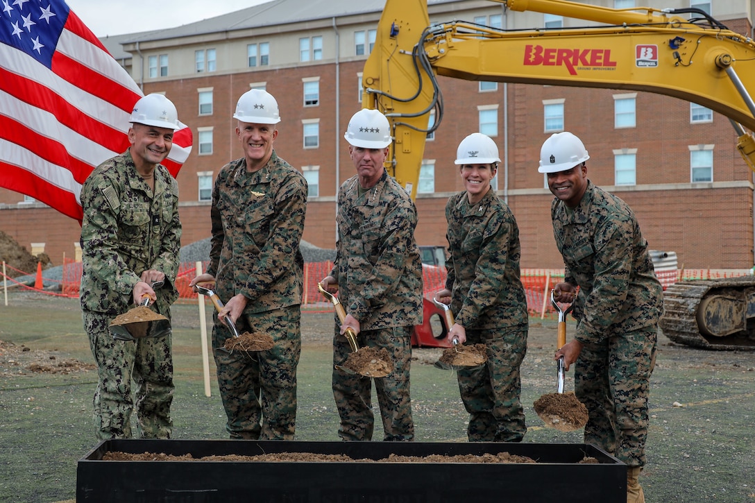 From left to right, U.S. Navy Rear Adm. Jorge Cuadros, Naval Facilities Engineering Systems Command Atlantic Commander, U.S. Marine Corps Maj. Gen. Jason Woodworth, commander of Marine Corps Installations Command and assistant deputy commandant for Marine Corps Installations and Logistics, Gen. Eric M. Smith, 39th Commandant of the Marine Corps, Col. Carrie Batson, commanding officer of Marine Barracks Washington, and Sgt. Maj. Jimmy F. Richard, sergeant major of Marine Barracks Washington, break ground during the P-158 groundbreaking ceremony at Marine Barracks Washington, D.C., Nov. 19, 2025. The new facility will feature 125 Bachelor Enlisted Quarters with added amenities such as a gym, cooking and meal preparation room, a Single Marine Program lounge and more. This project is part of the Marine Corps Barracks 2030 plan to improve the quality of life of Marines through meaningful near-term and long-term investments in barracks across the Corps. (U.S. Marine Corps photo by Cpl. Christopher Prelle)