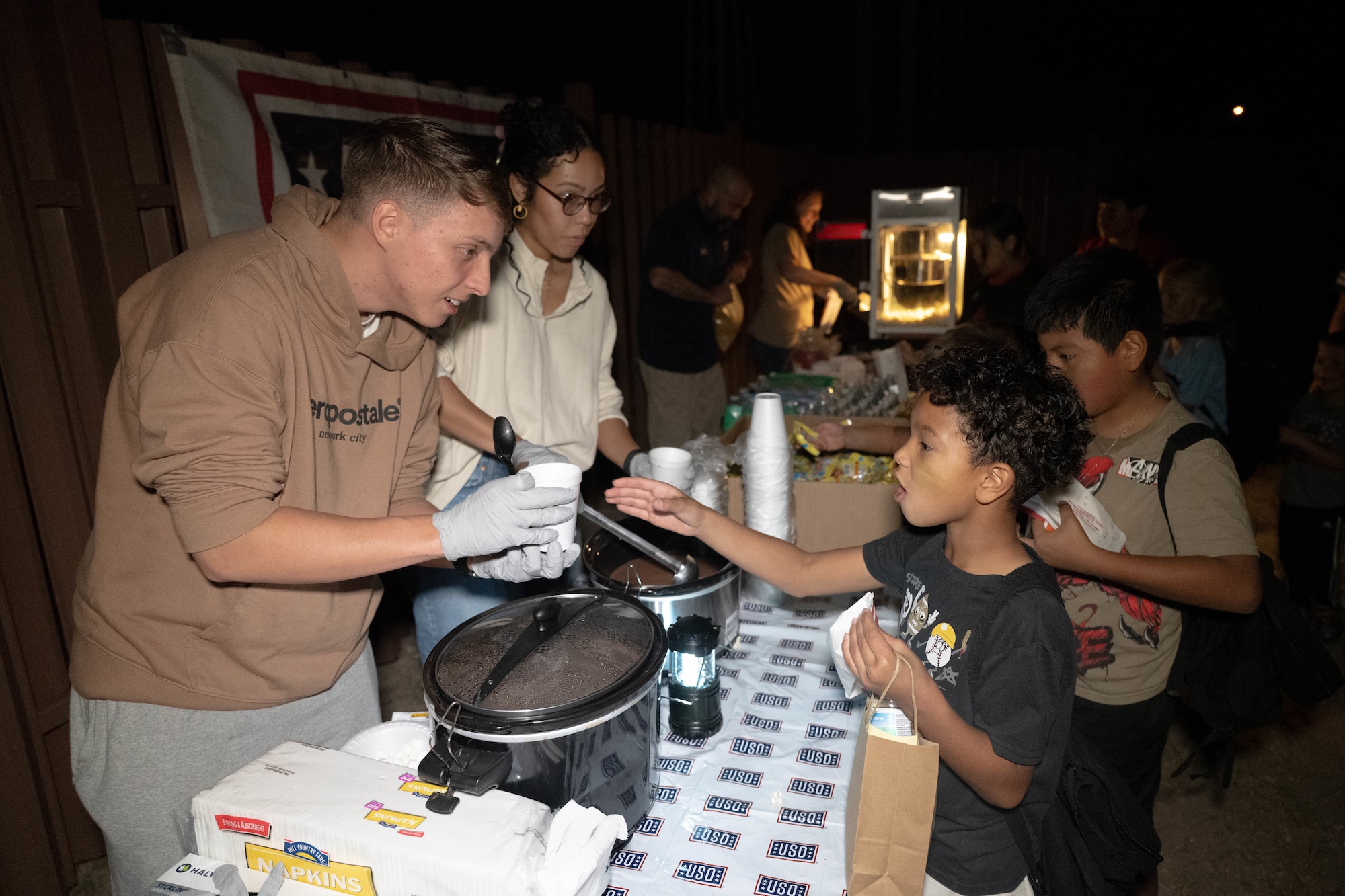 USO employees prepare hot chocolate for Junior Deployment participants during a Junior Deployment event at Laughlin Air Force Base, Texas, Nov. 21, 2025. The USO welcomed returning participants from their mock deployment with food, drinks and entertainment. (U.S. Air Force photo by Airman 1st Class Darryl Keith)