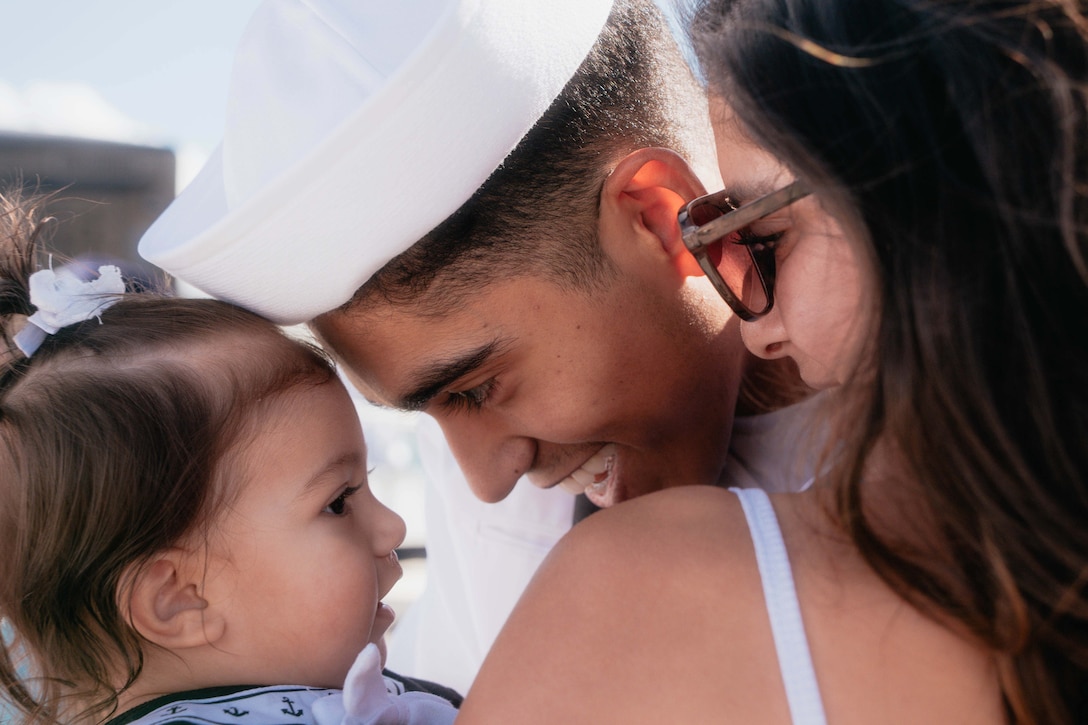 A close-up of a sailor, mother and baby huddled together.