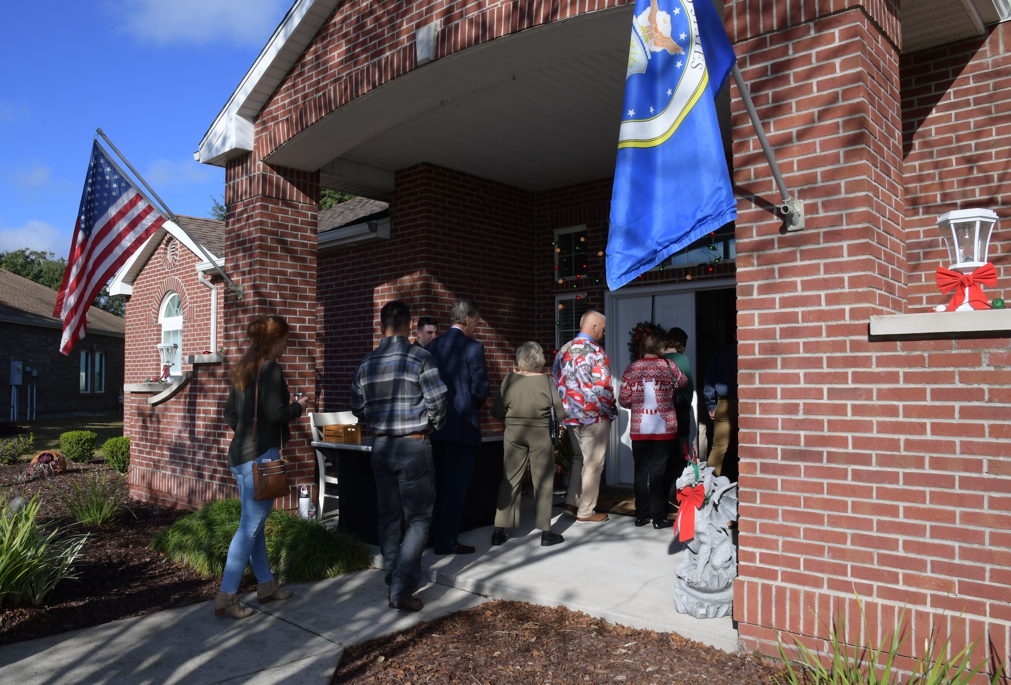 A group of people walk into a house.