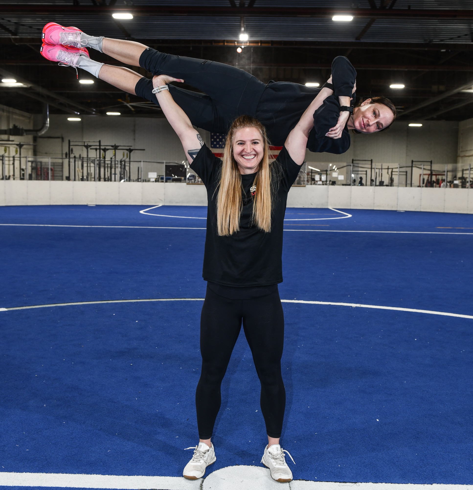 Kat Moake, physical training coach, preforms a Military press using Lt. Col. Caitlin Oviatt, 55th Logistics Readiness Squadron commander, as her barbell at the Offutt Field House, December 12, 2025. (U.S. Air Force photo by Chad Watkins)