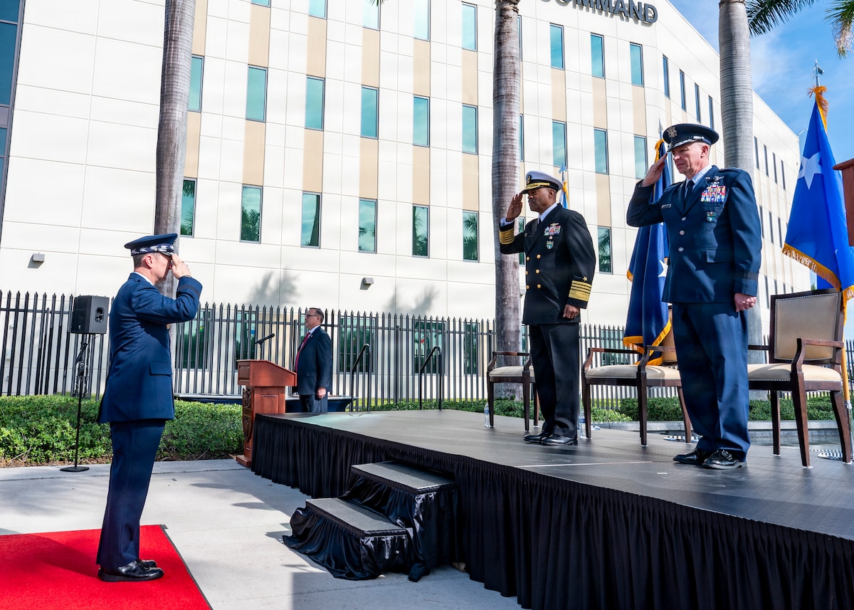 Men in dress military uniforms salute each other.
