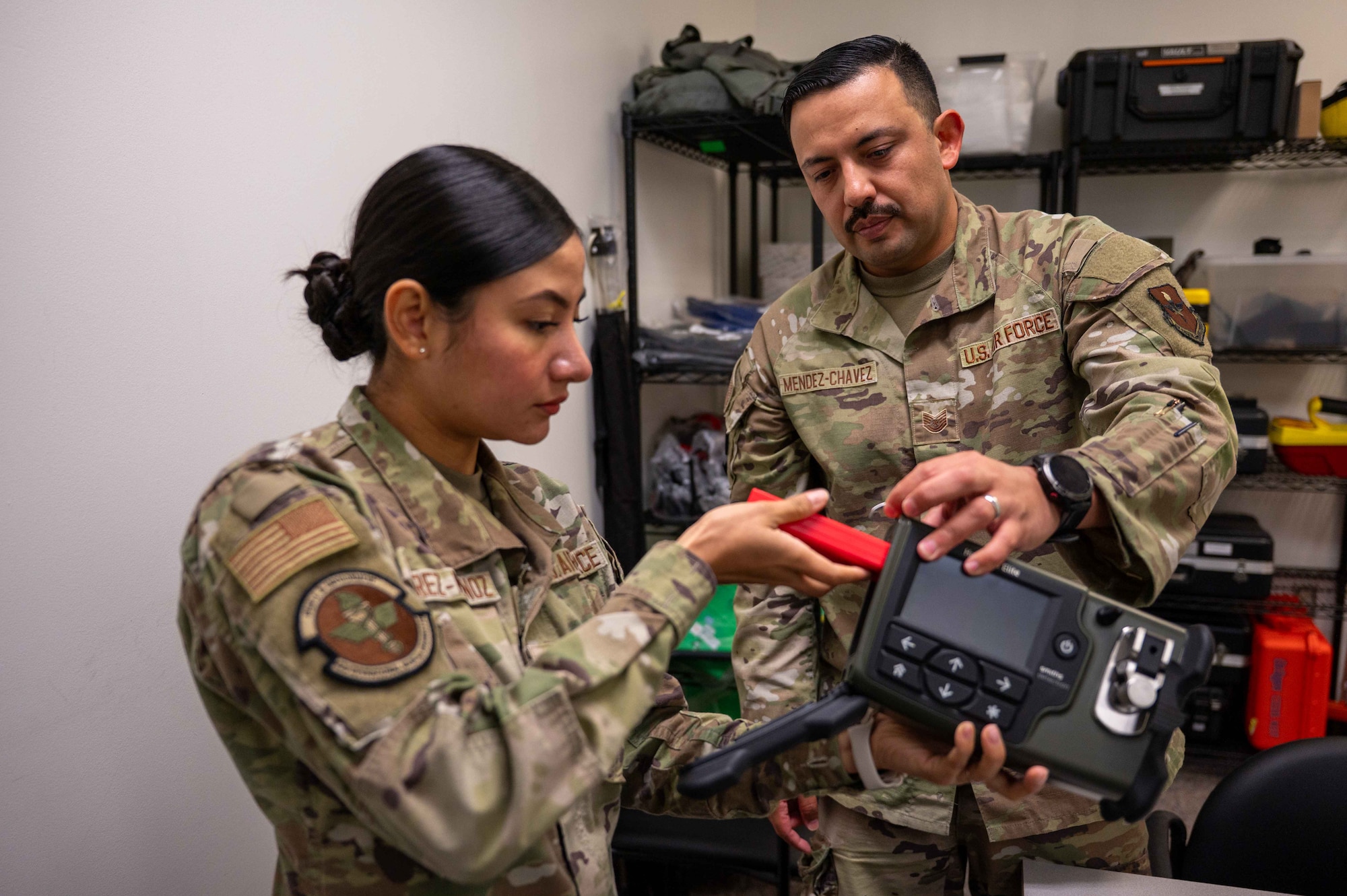 U.S. Air Force Tech. Sgt. Hector Mendez-Chavez, bioenvironmental engineering flight chief, Maxwell Medical Group, instructs Airman 1st Class Arely Ramirez-Munoz, bioenvironmental engineering technician, Maxwell Medical Group BEE flight, on how to calibrate a handheld hazardous material identifier at Maxwell Air Force base, Alabama, Oct. 30, 2025. The identifier is used by the bioenvironmental engineering team to identify unknown solid and liquid chemicals in the field. (U.S. Air Force photo by Senior Airman Evan Porter)