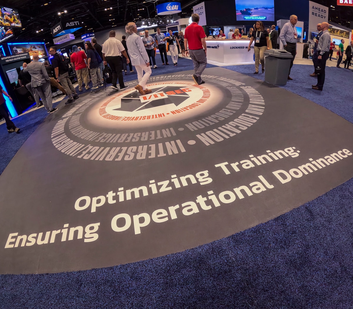 Image shows a light shining on a floor to make the words Optimizing Training Ensuring Operational Dominance. The carpet is blue.