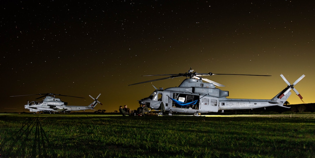 A U.S. Marine Corps AH-1Z Viper and a UH-1Y Venom assigned to Marine Light Attack Helicopter Squadron (HMLA) 367, Marine Aircraft Group 39, 3rd Marine Aircraft Wing, park on an airfield overnight during Exercise Steel Knight 25 on San Clemente Island, California, Dec. 9, 2025. Steel Knight is an annual exercise that strengthens the Navy-Marine Corps team's ability to respond forward, integrate across domains, and sustain Marine Air-Ground Task Force readiness. (U.S. Marine Corps photo by Sgt. Atticus Martinez)