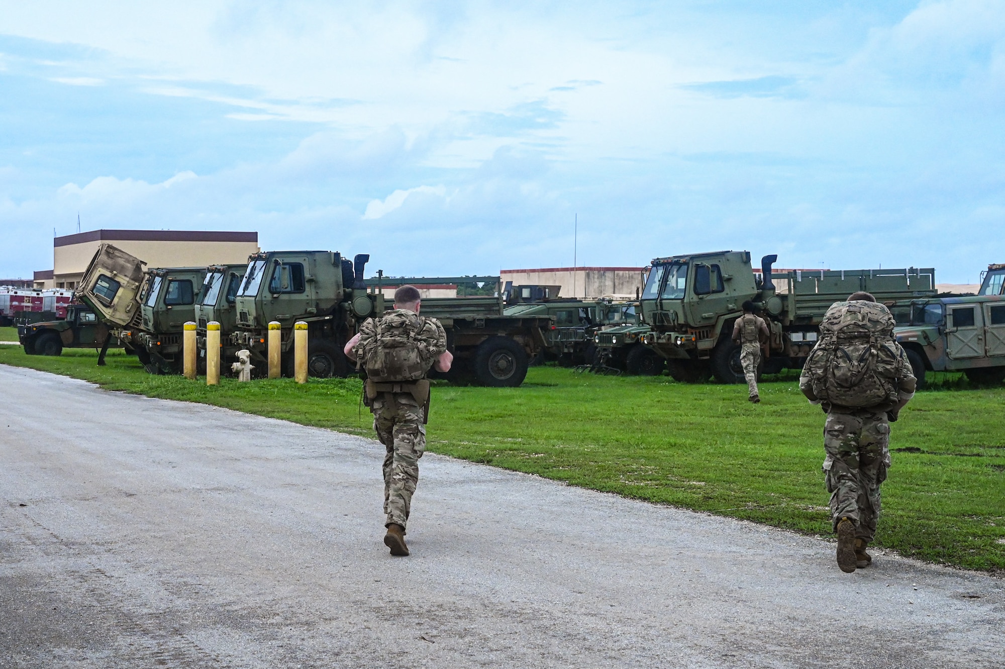 U.S. Air Force Airmen from the 824th Base Defense Squadron and the 11th Combat Air Base Squadron ruck across a road and field to reach another tactical training point at Andersen Air Force Base, Guam, Nov. 7, 2025.