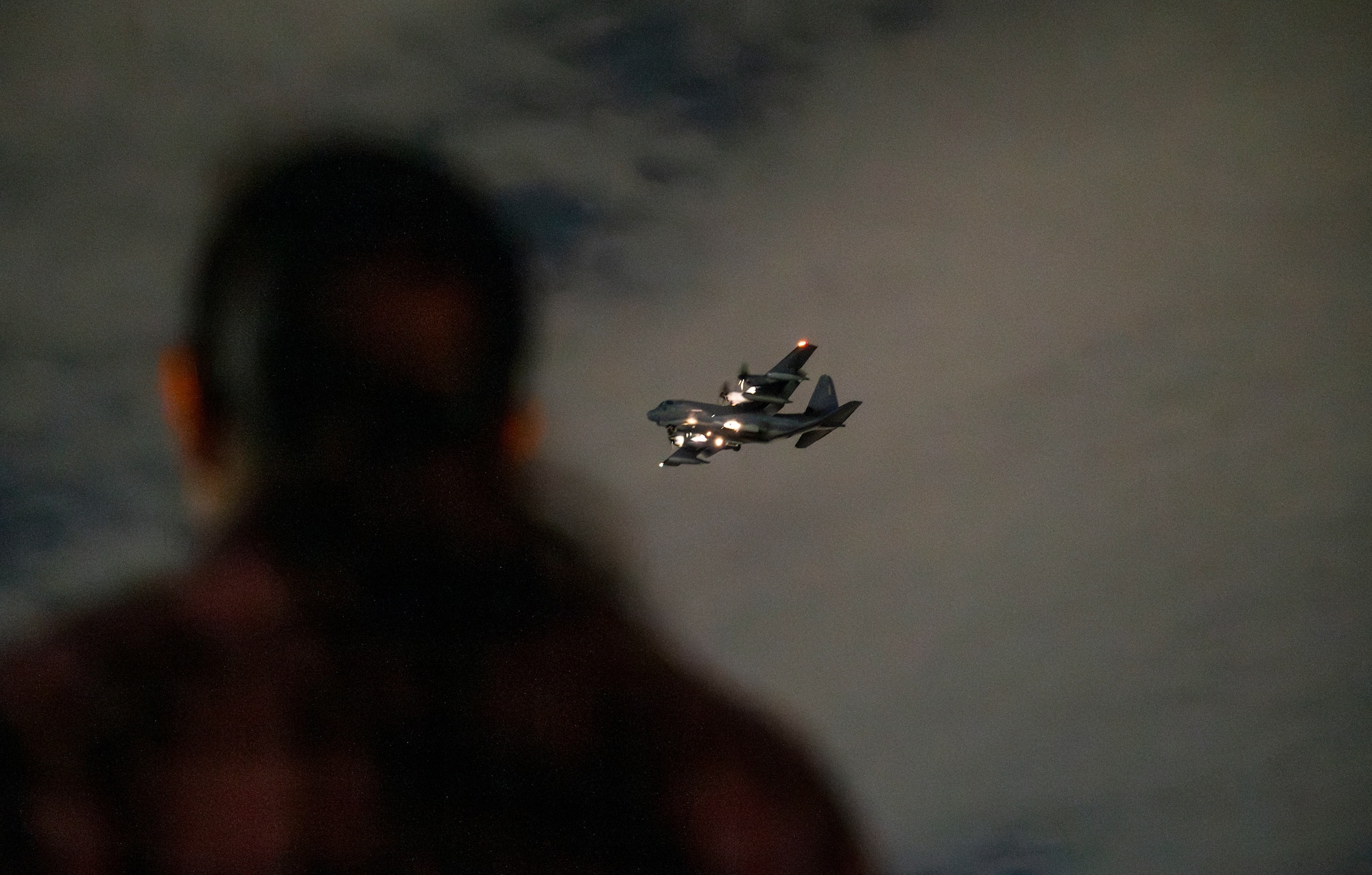 U.S. Air Force Senior Airman Nayeli Lopez, 18th Operations Support Squadron airfield management journeyman, observes a C-130J Super Hercules assigned to the 353rd Special Operations Wing, flying above Kadena Air Base, Japan, Dec. 11, 2025.