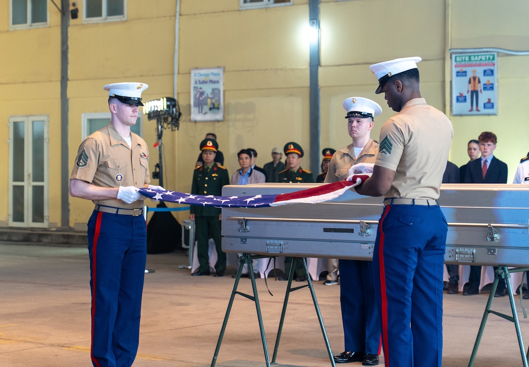 Two members of the U.S. Marine Corps. unfold an American flag during the 171st Repatriation Ceremony at the Gia Lam Airfield, Hanoi, Vietnam, on Dec. 13, 2025.