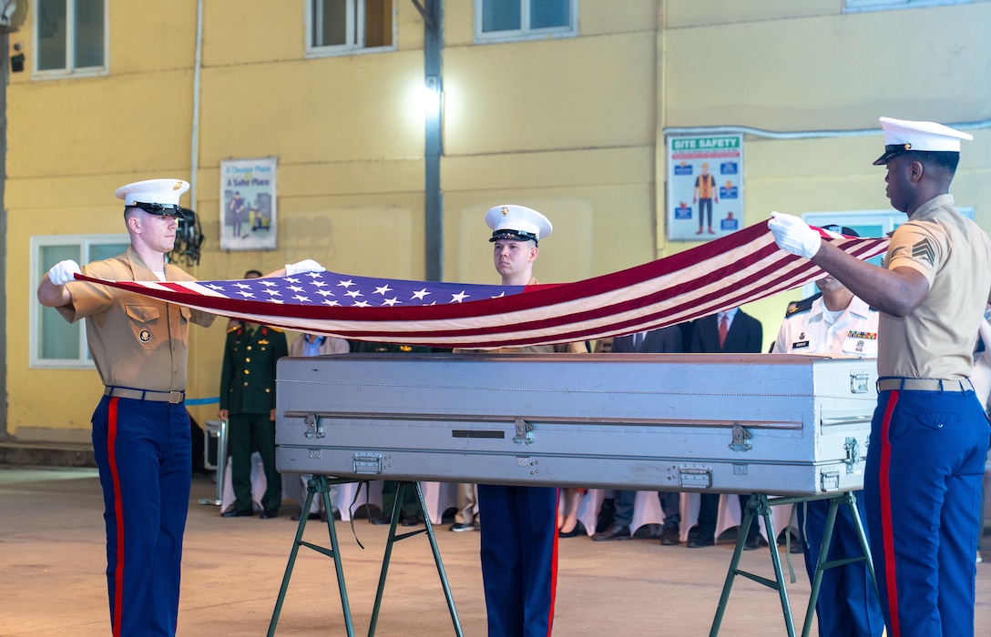 Two members of the U.S. Marine Corps. prepare to drape an American flag over a transport case that contains potential U.S. service member remains during the 171st Repatriation Ceremony at the Gia Lam Airfield, Hanoi, Vietnam, on Dec. 13, 2025.